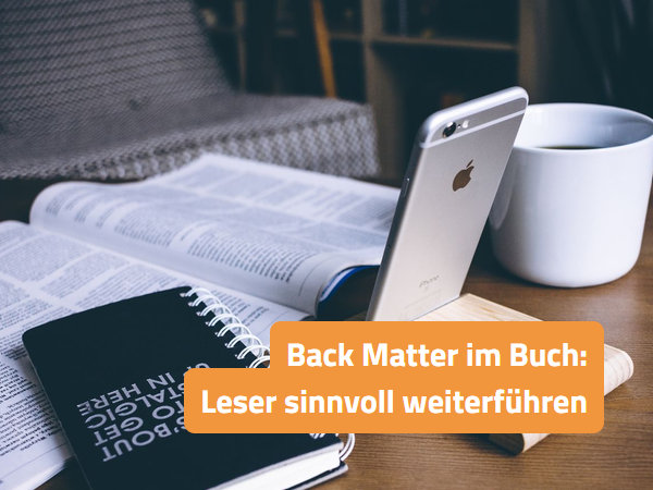 Aufgeschlagenes Buch, daneben ein aufgestelltes Smartphone und eine Tasse Kaffee